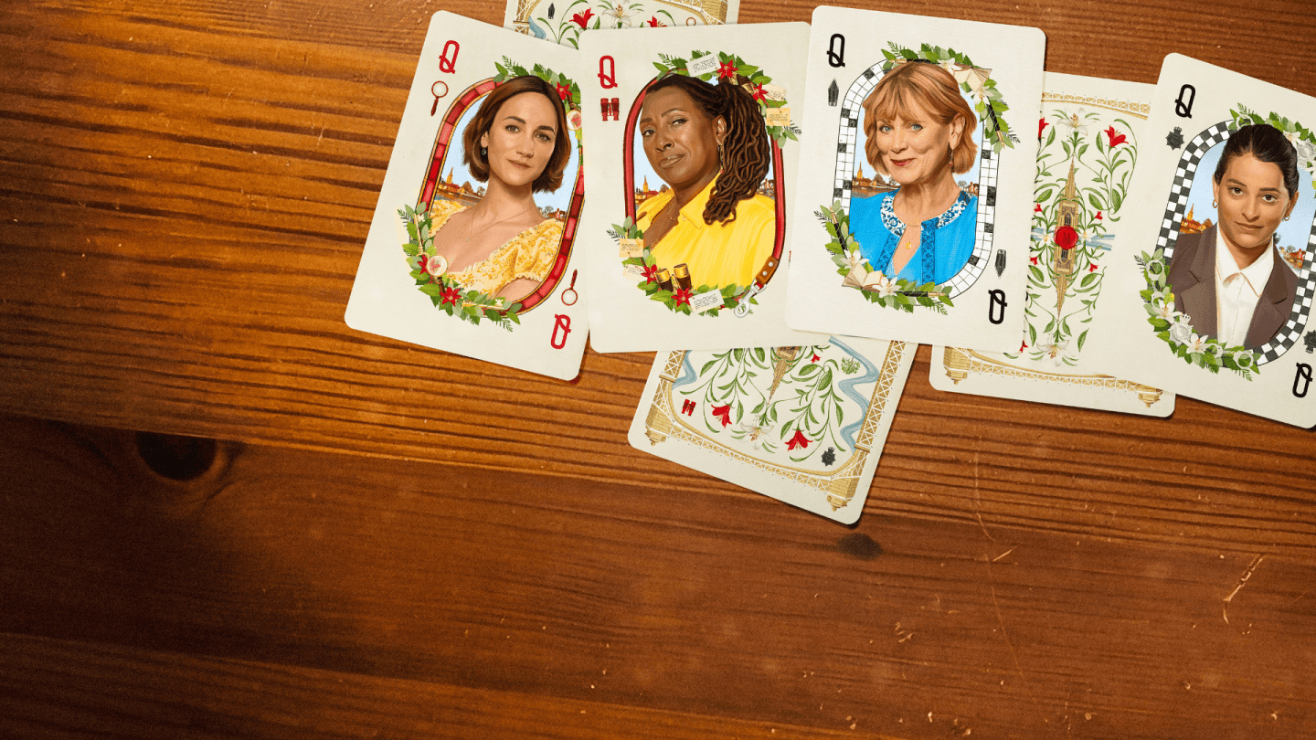A spread of decorative playing cards featuring illustrated portraits on a wooden tabletop.