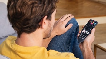 A photograph of a person holding a Freesat remote control