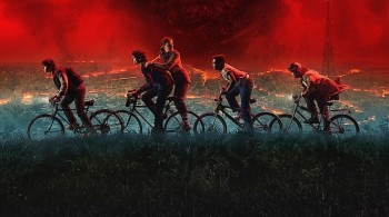 Five teenagers on bikes riding in front of a red sky and a city 