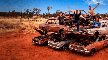 Four people stood on a pile of old rusty cars in the Australian Outback for the show Outback Wreckers