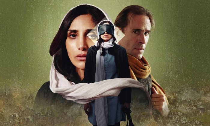 A women blindfolded wearing a hijab stood against a green background