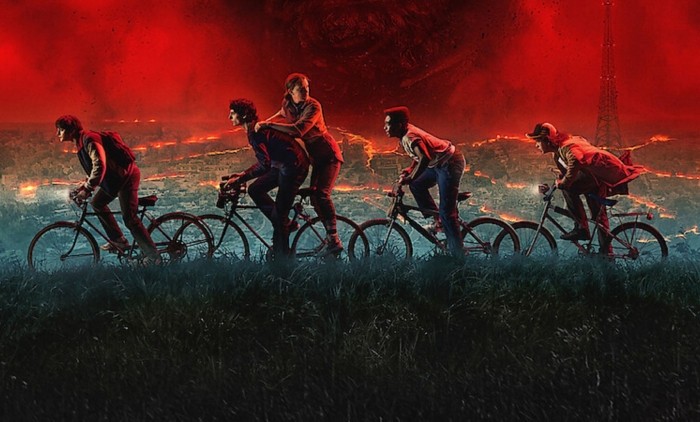 Five teenagers on bikes riding in front of a red sky and a city 