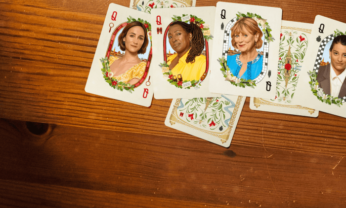 A spread of decorative playing cards featuring illustrated portraits on a wooden tabletop.