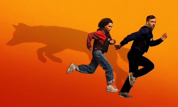 Two people sprint across an orange background while a large wolf shadow follows behind, symbolising pursuit, danger and survival in a thriller drama.