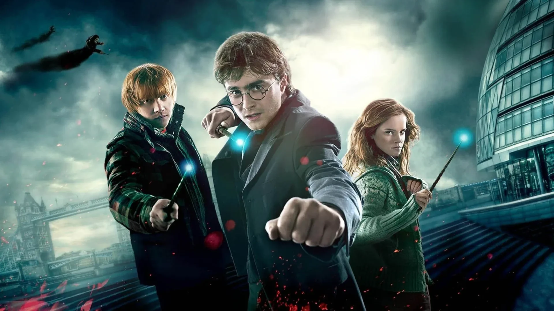 Daniel Radcliff, Rupert Grint and Emma Watson in Harry Potterand the Deathly Hallows part 1 holding wands against a dreary background