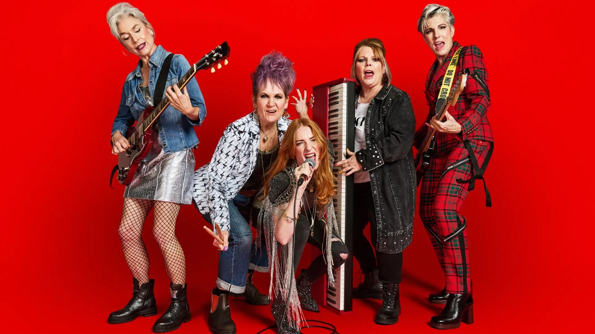 Rosalie Craig, Joanna Scanlan, Tamsin Greig, Amelia Bullmore and Lorraine Ashmbourne posing with instruments against a red background in the BBC drama Riot Women