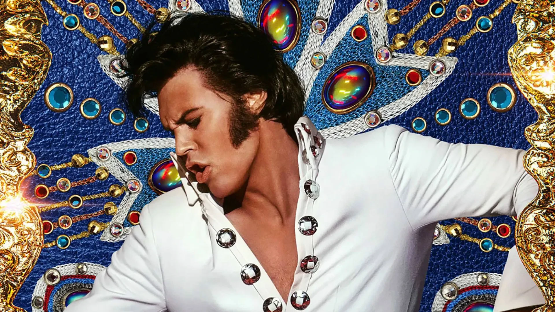 Promotional image from the film Elvis (2022), showing a person in a white jumpsuit with jewel-like buttons, posed against an ornate, colourful backdrop decorated with gold and vibrant patterns.