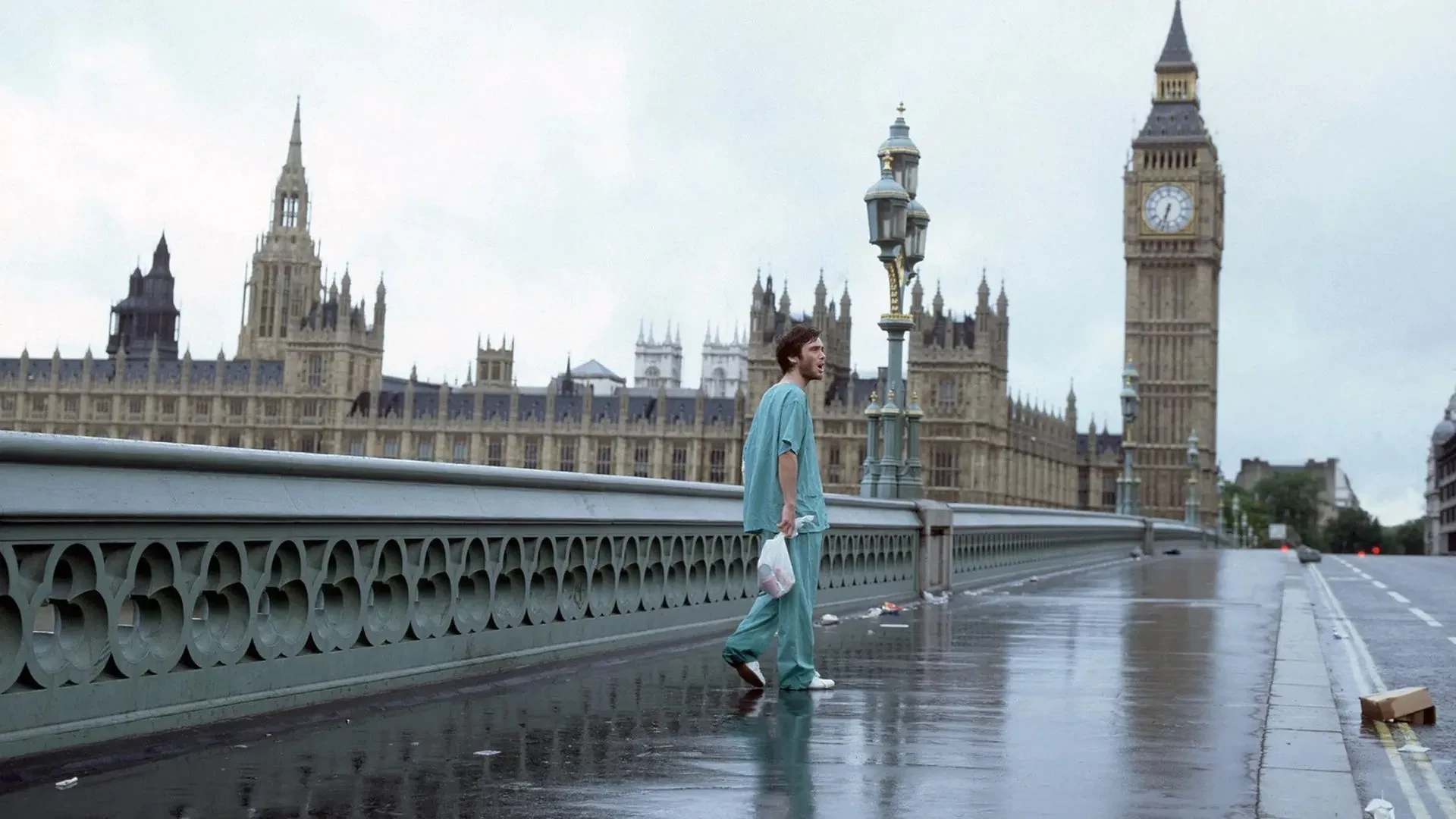 Person in hospital scrubs walks across an empty Westminster Bridge on a rainy day, with Big Ben and the Houses of Parliament in the background