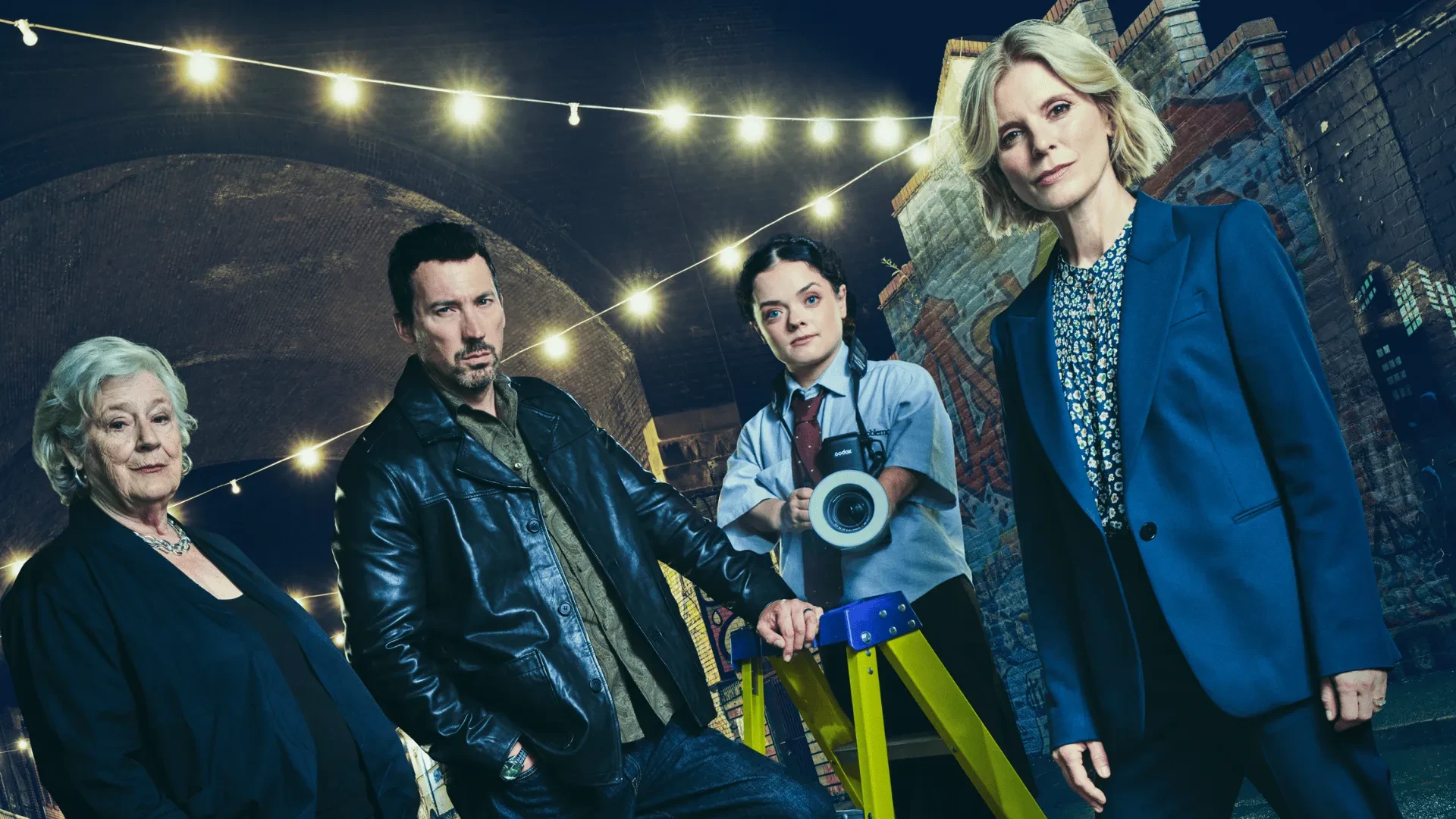 Team of investigators standing under string lights in an urban alleyway at a marked crime scene location.