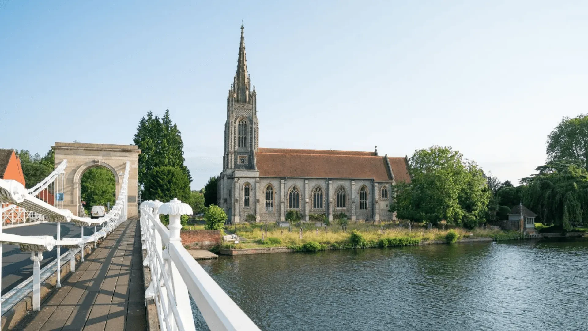 Historic riverside church with a tall spire in Marlow, viewed from the suspension bridge overlooking the water