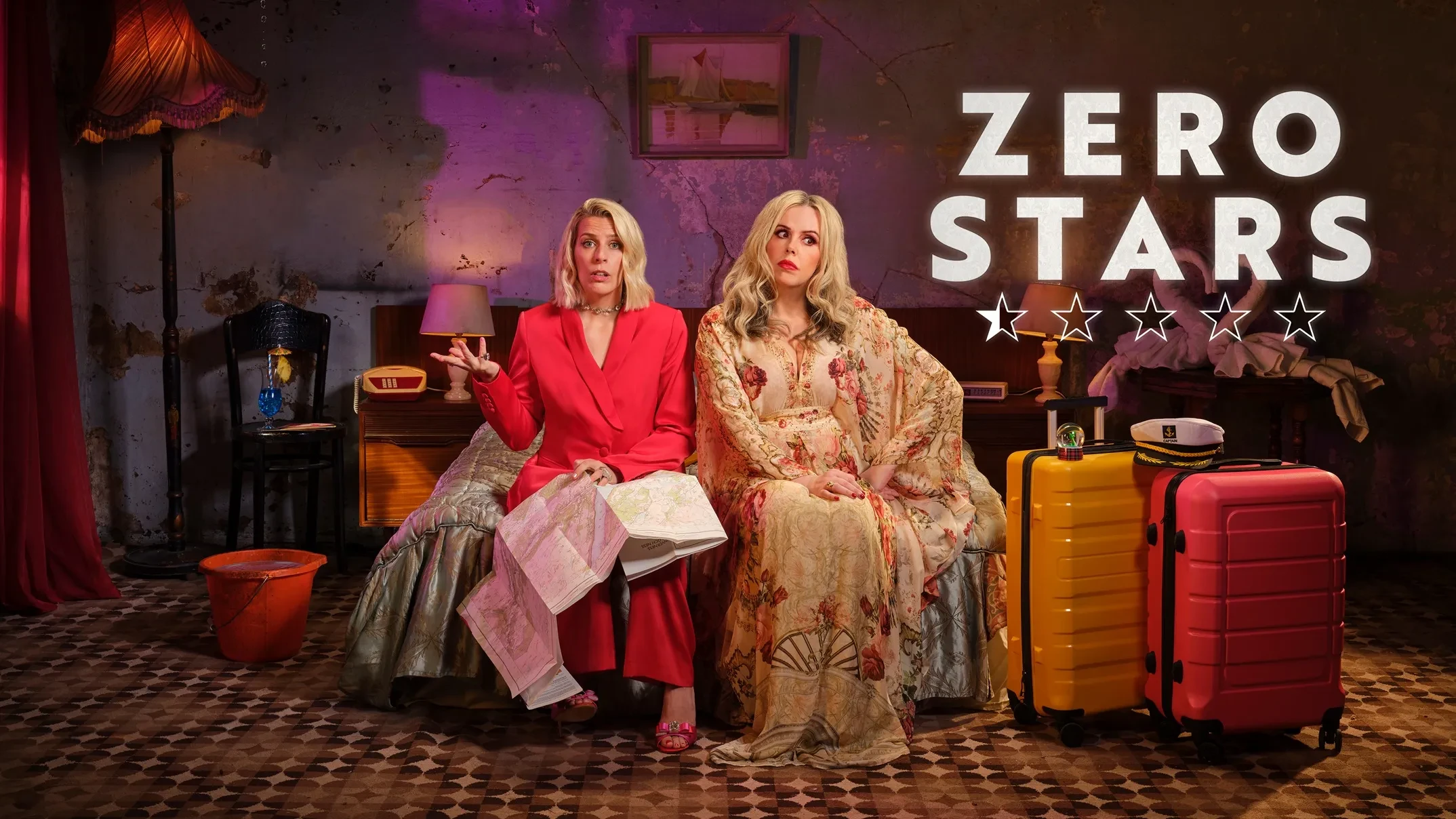 Key art for Zero Stars shows Roisin Conaty and Sara Pascoe sitting on a bed next to suitcases