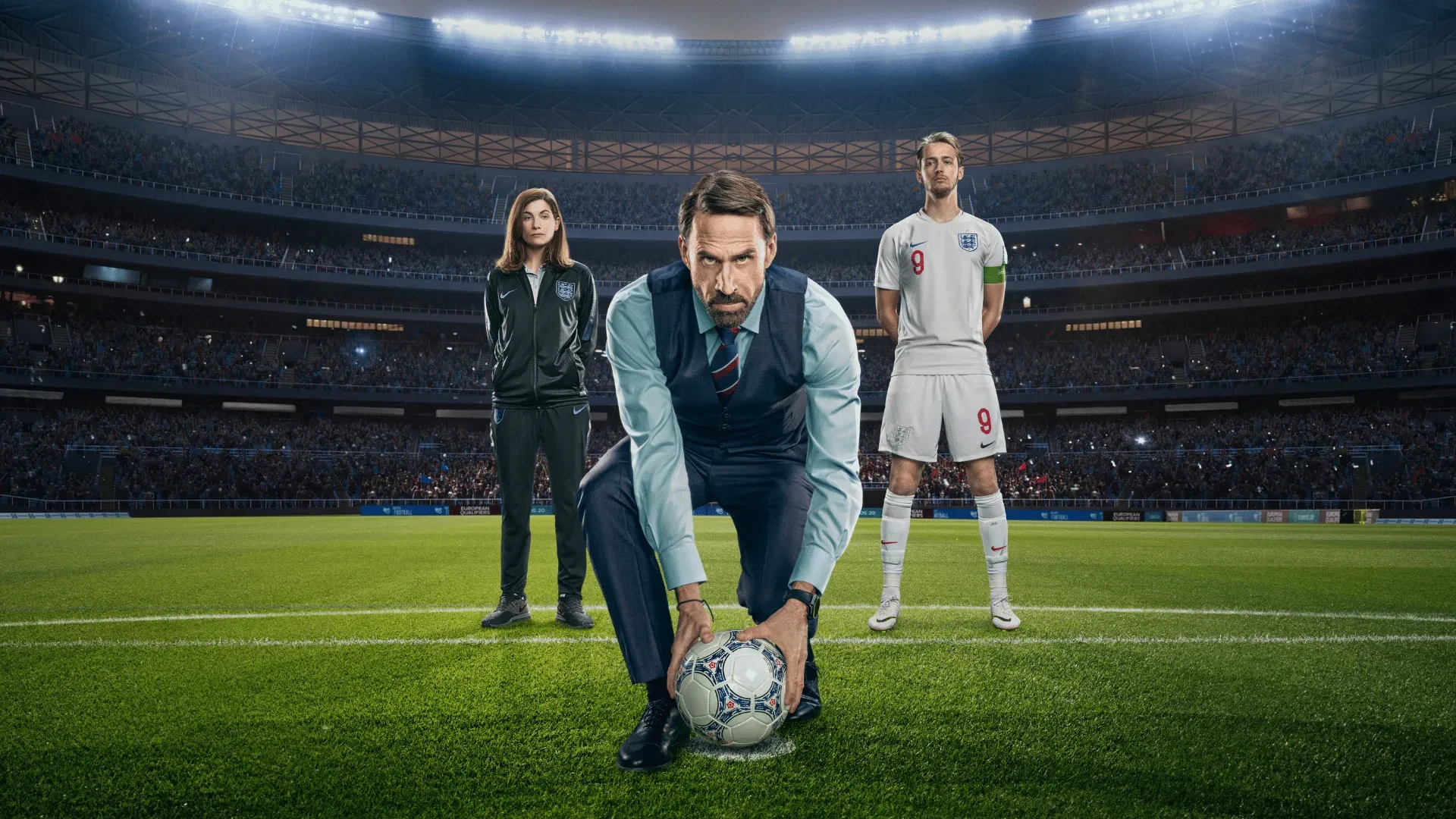England football team manager placing ball on pitch in floodlit stadium with players behind, dramatic sports scene