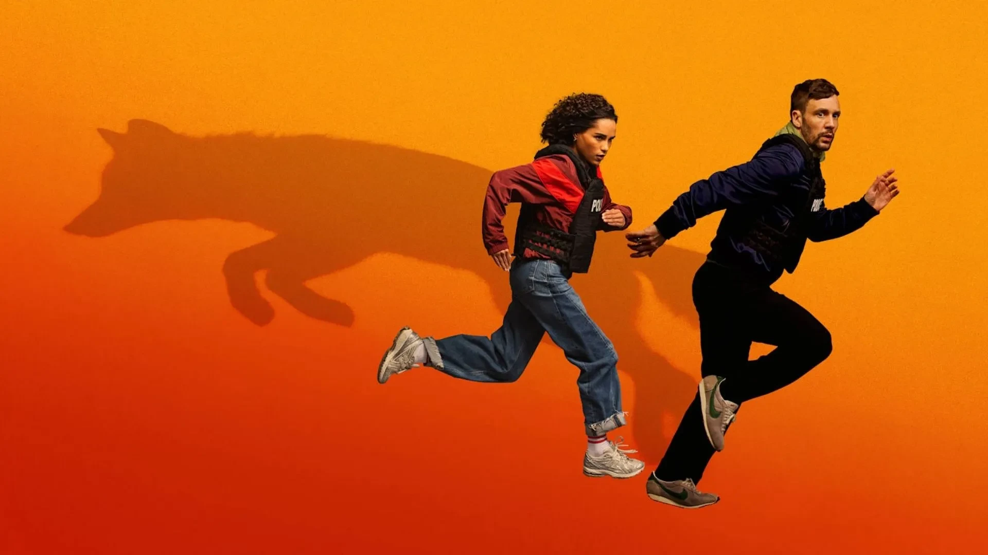 Two people sprint across an orange background while a large wolf shadow follows behind, symbolising pursuit, danger and survival in a thriller drama.