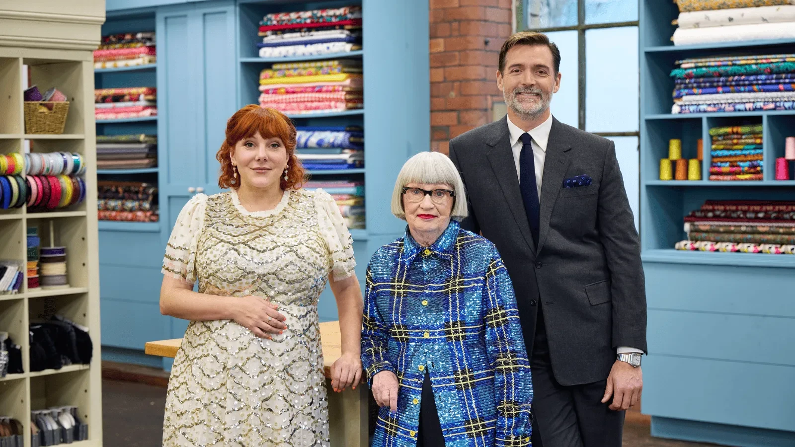 Promotional image for The Great British Sewing Bee shows Kiell Smith-Bynoe alongside judges Esme Young and Patrick Grant
