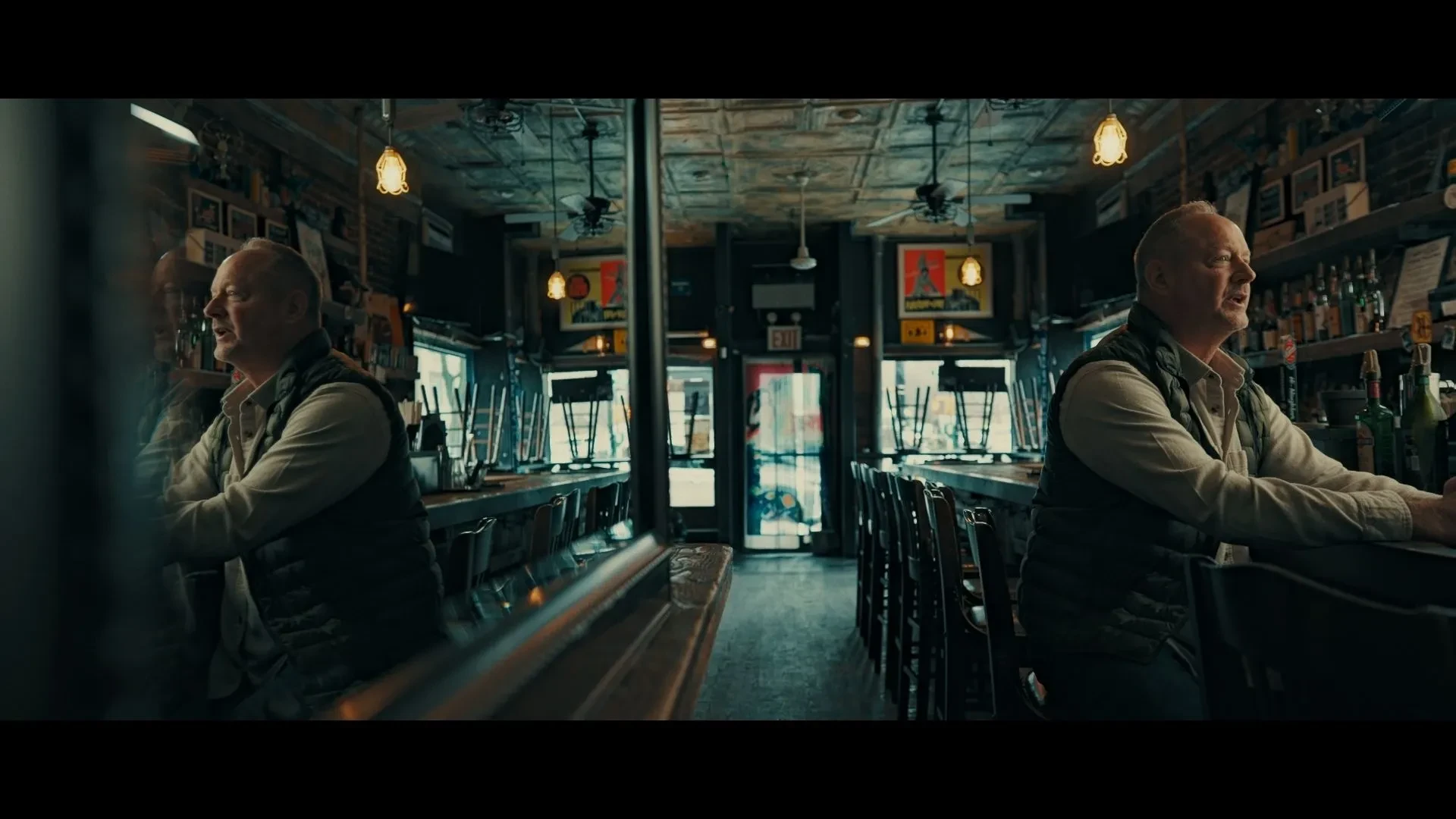 Person seated alone at a bar inside a dimly lit pub, with reflections in a mirror creating a cinematic atmosphere suggestive of mystery and espionage.