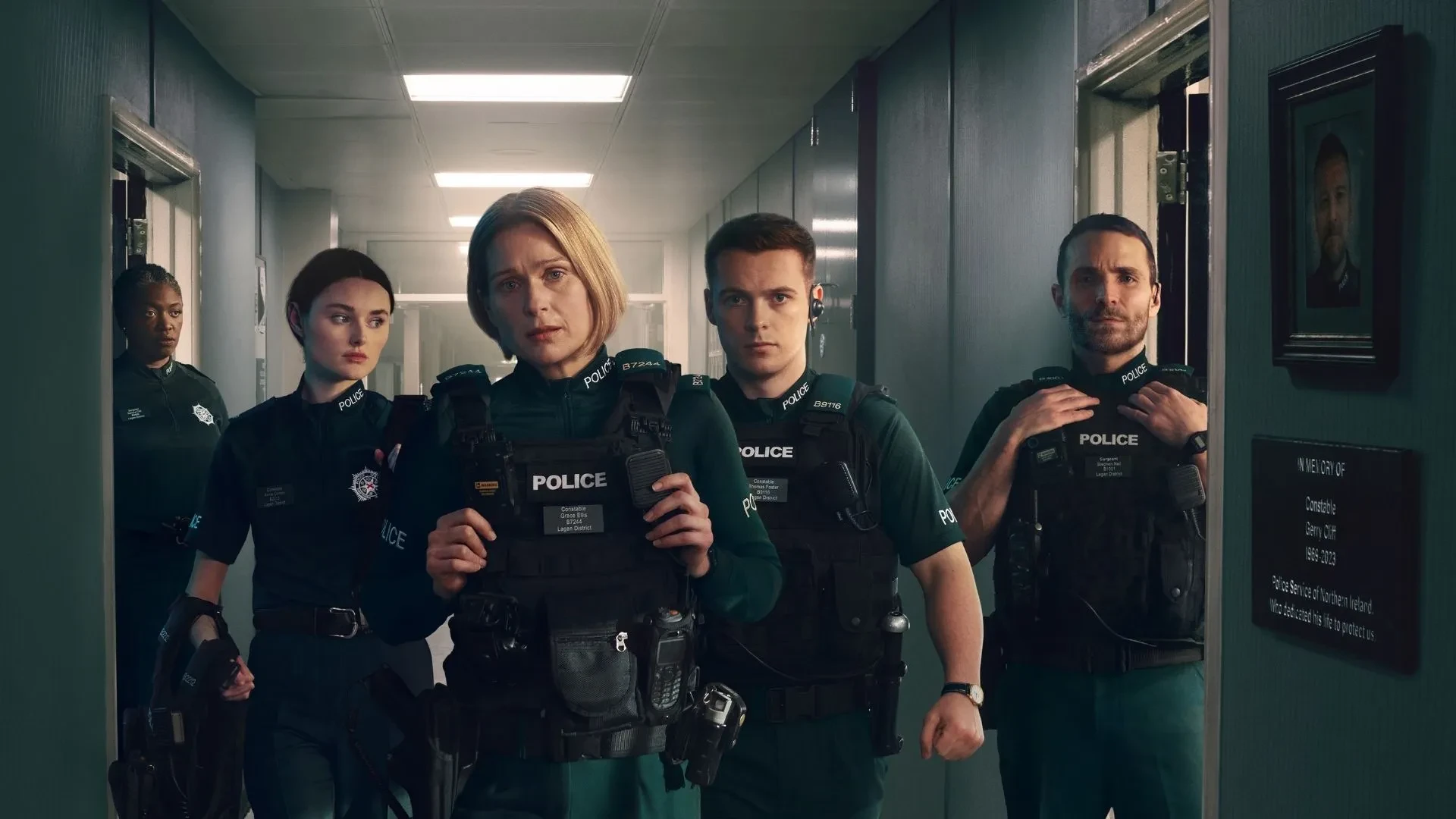 Blue Lights TV drama cast members in police uniforms inside a station corridor during a tense scene.