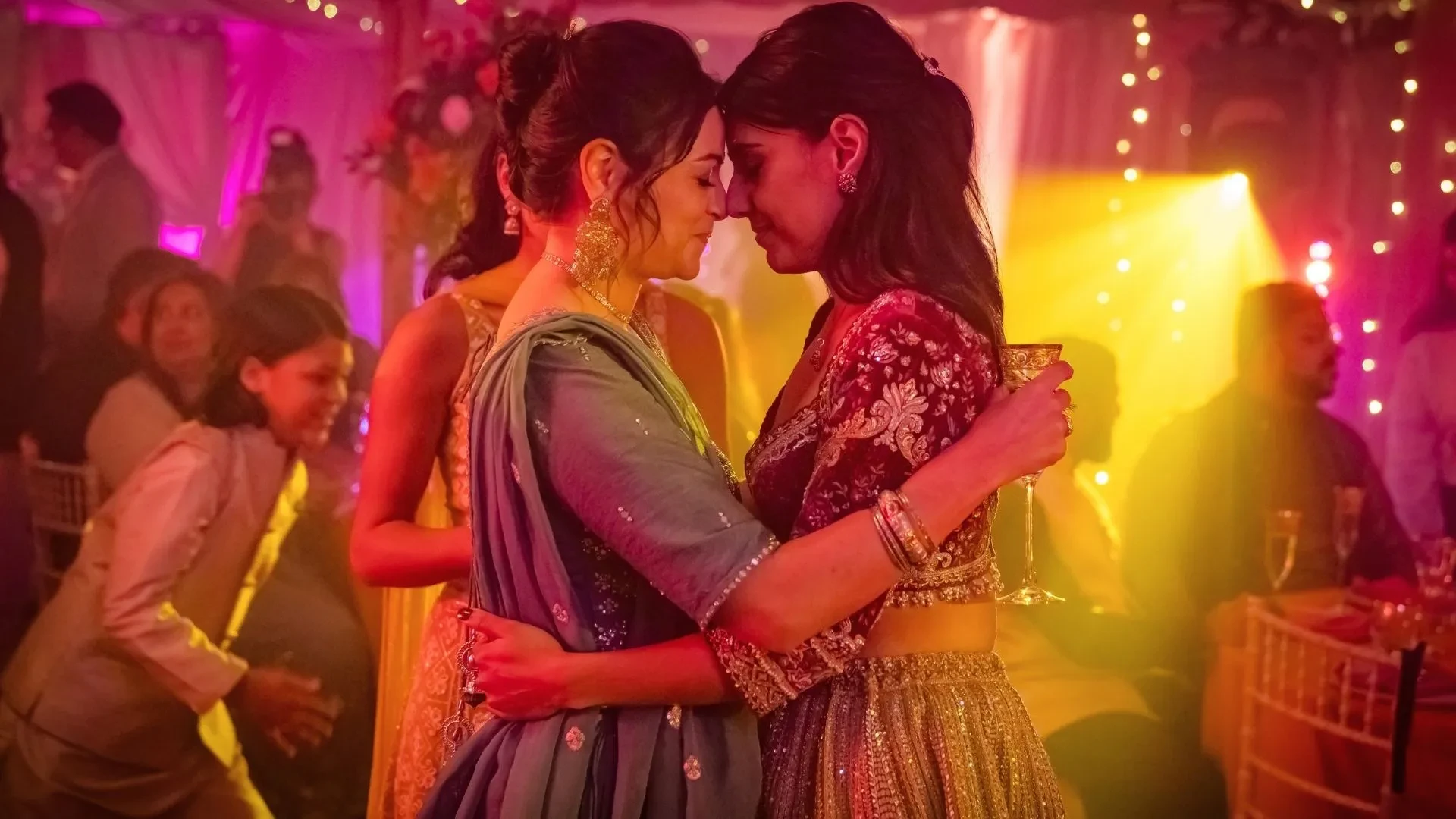 Promotional image for Split Up showing two characters embracing at a colourful party with festive lights and guests in the background