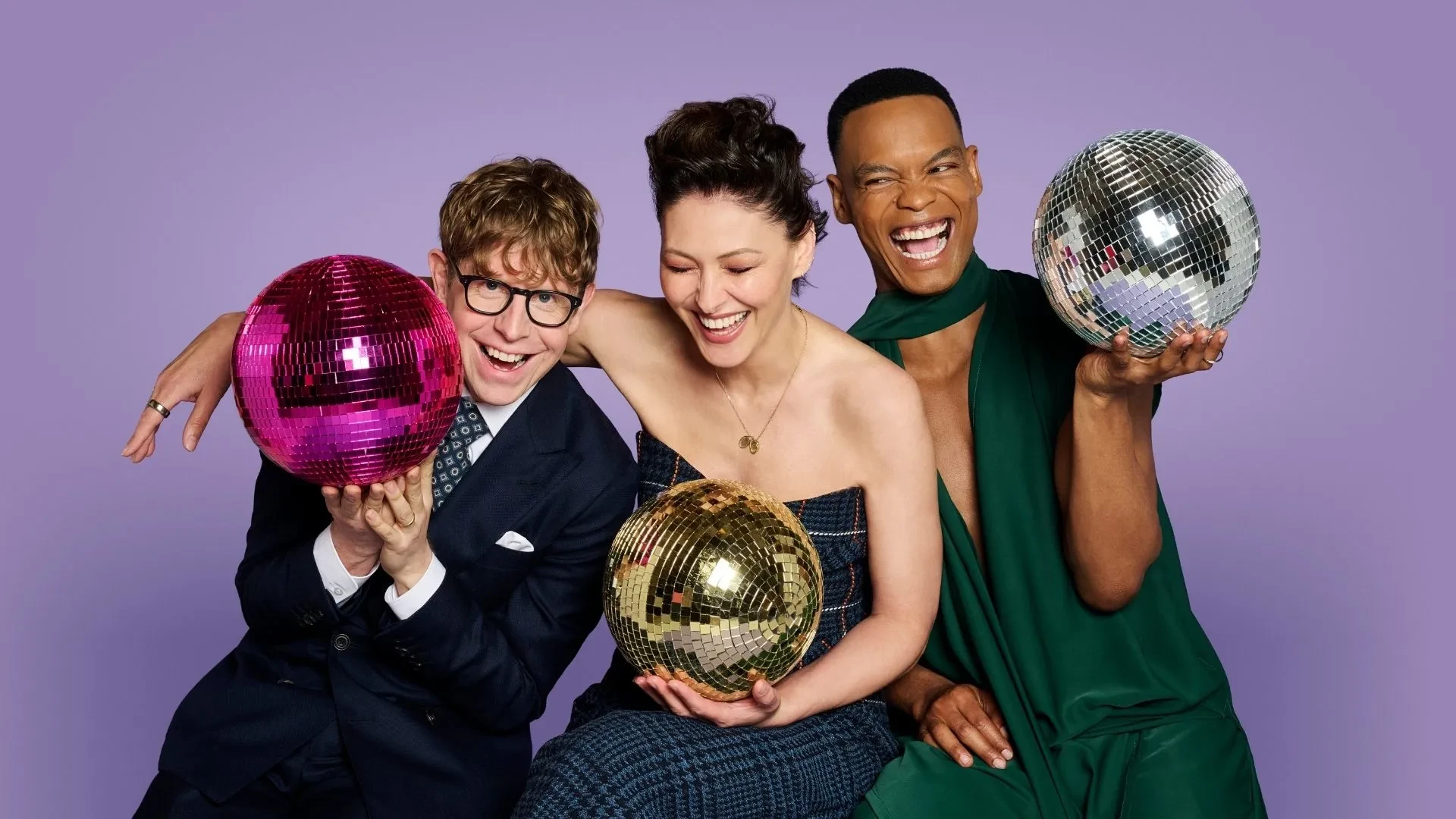Promotional image for Strictly Come Dancing featuring three presenters holding colourful disco balls against a purple studio background.