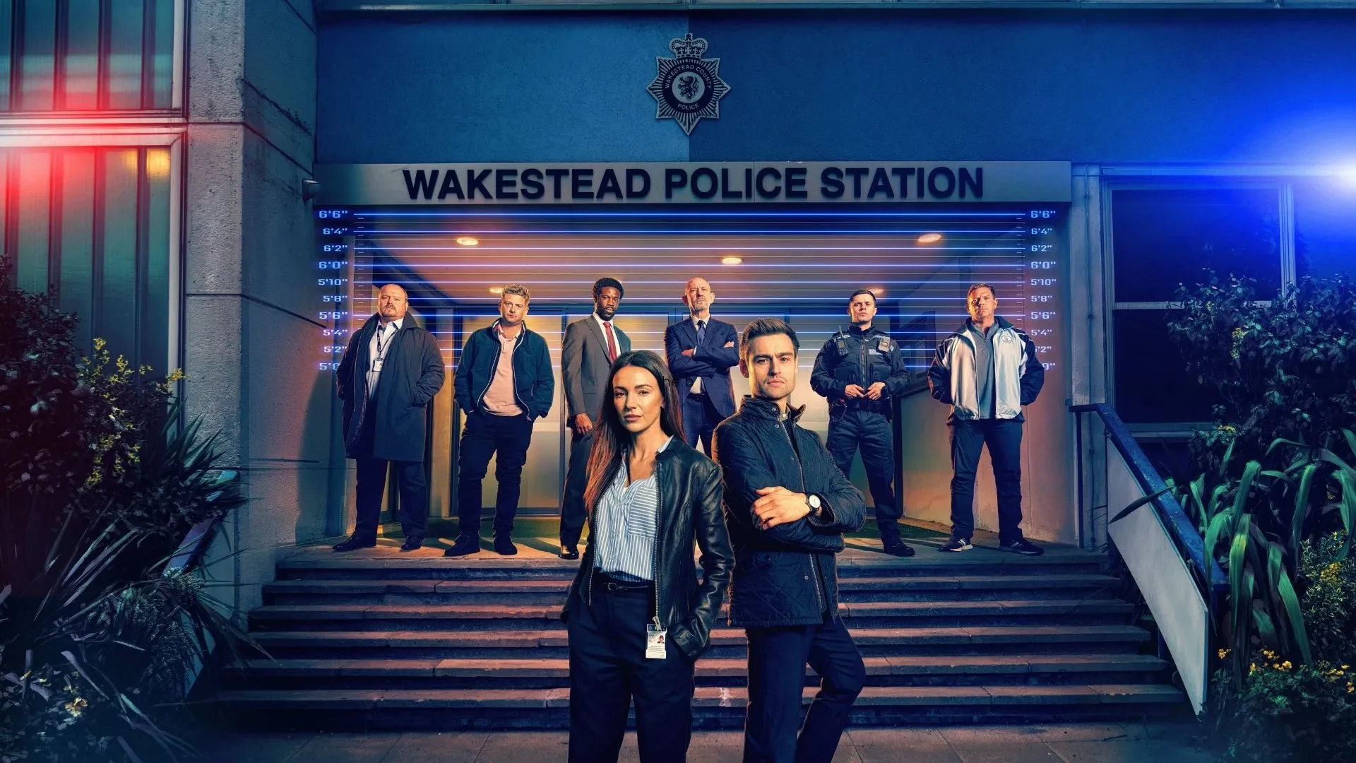 Official cast photo for The Blame crime drama outside Wakestead Police Station with emergency lights